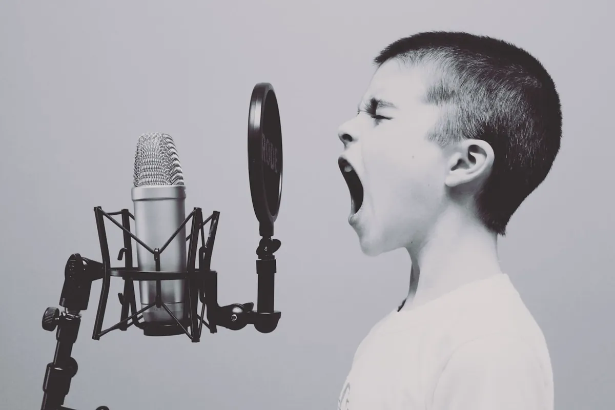 Niño gritando frente a un micrófono de estudio en blanco y negro