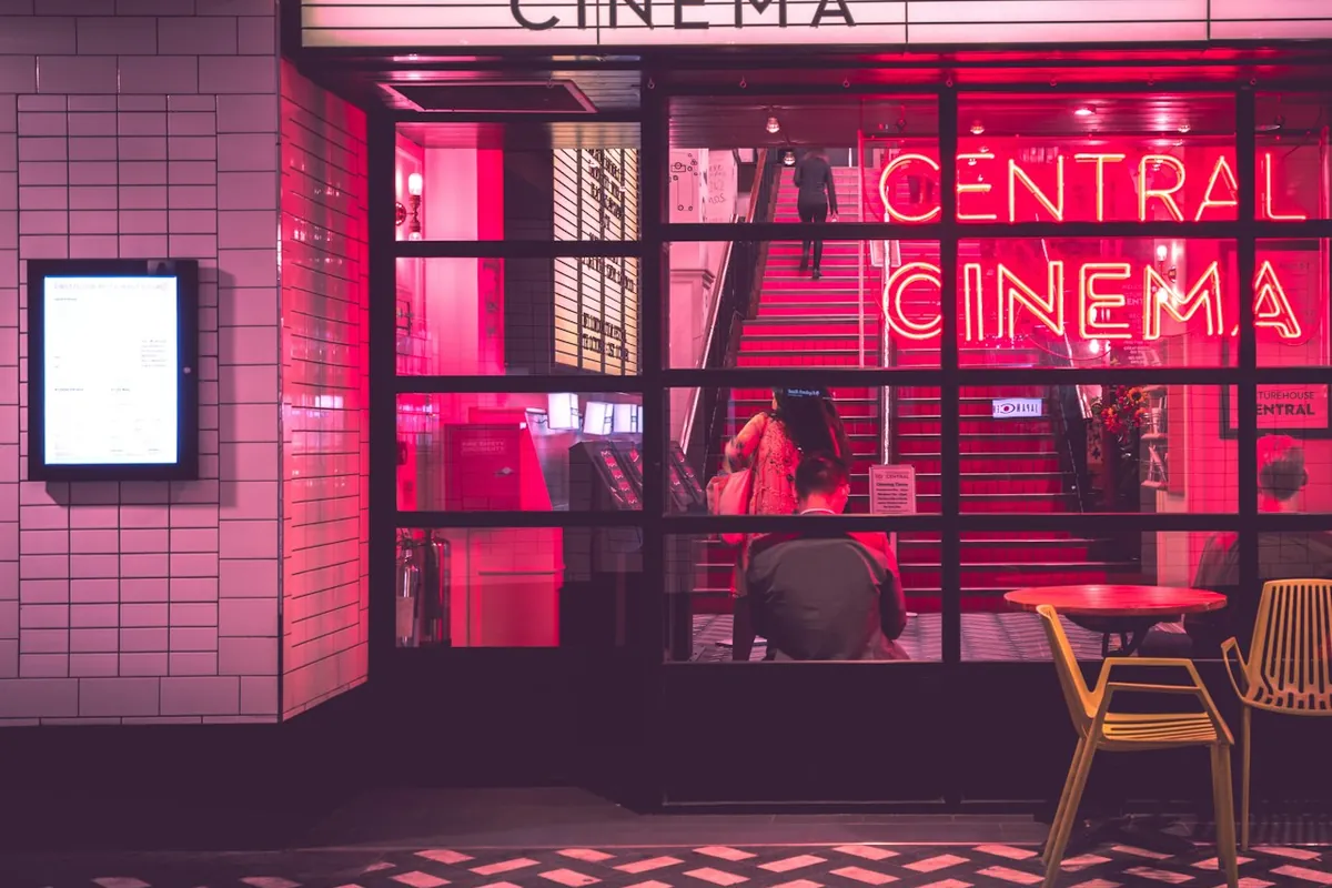 Fachada de cine con luces de neón rosadas y rojas